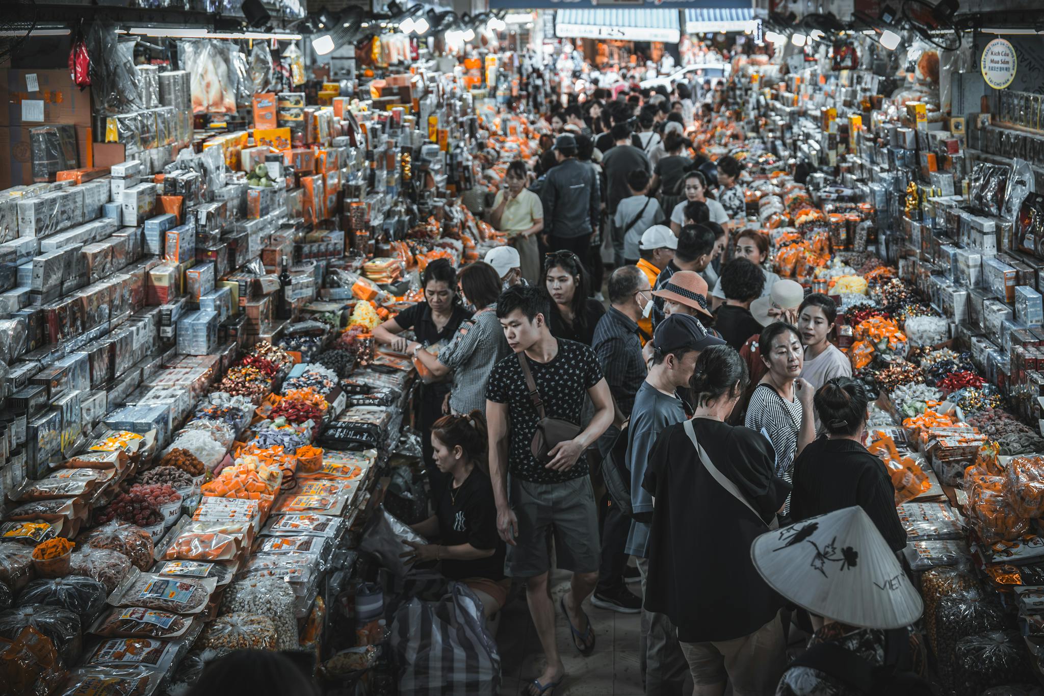 Busy indoor market filled with shoppers and colorful goods.